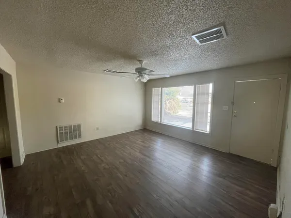 an empty room with wooden floor and windows