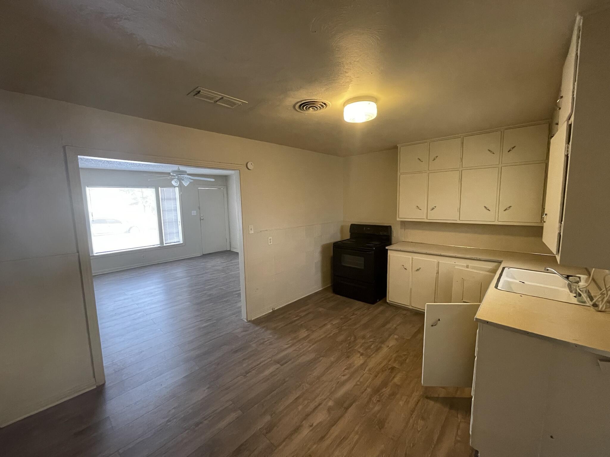 4303 42nd Street Lubbock, TX 79413 - Photo 5 of 10 a view of a kitchen with a sink dishwasher cabinets and wooden floor