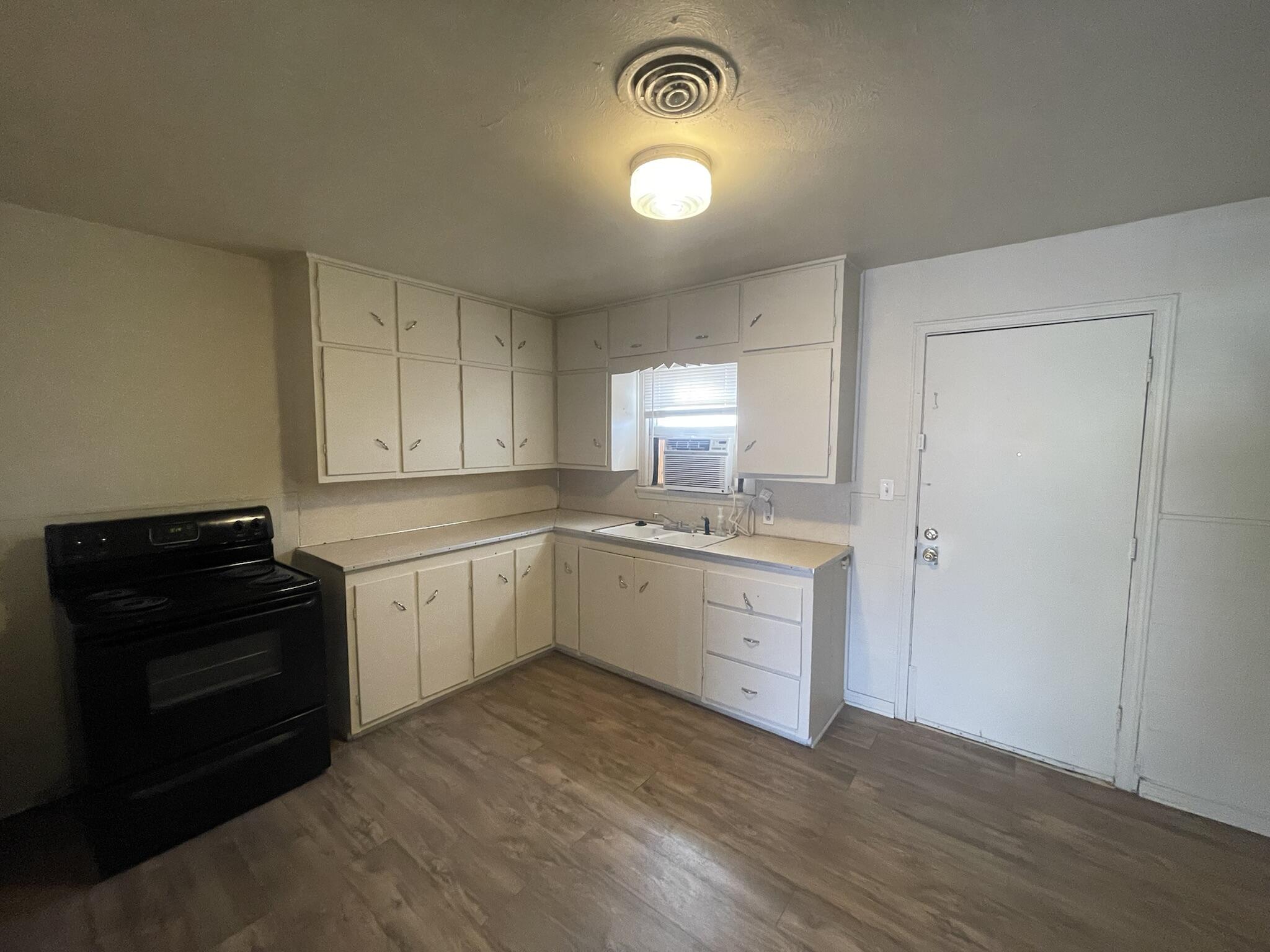 4303 42nd Street Lubbock, TX 79413 - Photo 6 of 10 a kitchen with a white cabinets and black appliances
