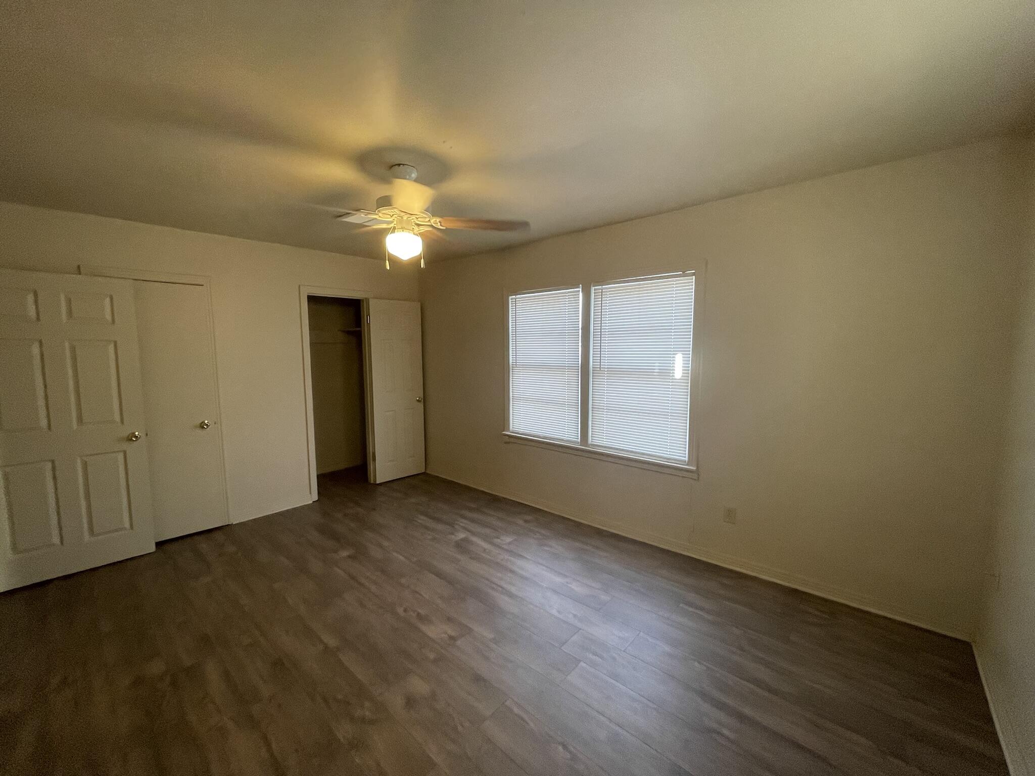 4303 42nd Street Lubbock, TX 79413 - Photo 7 of 10 an empty room with wooden floor chandelier fan and windows