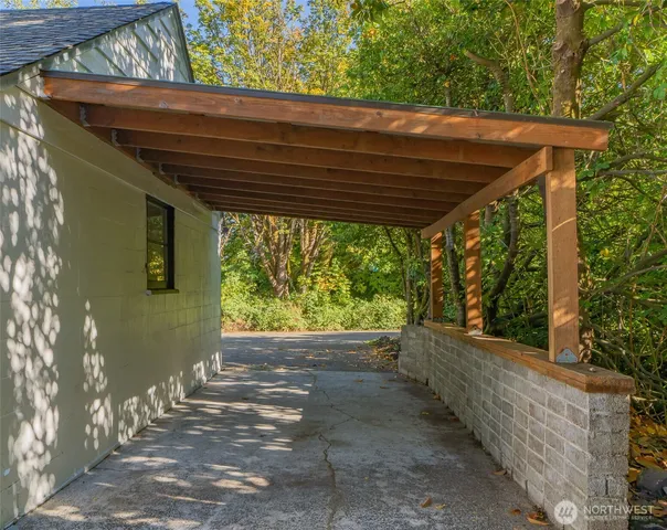 a backyard of a house with large trees and a wooden fence