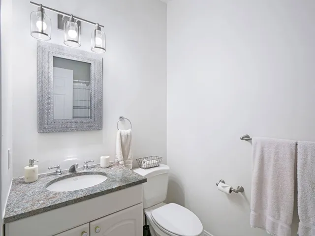 a bathroom with a granite countertop sink toilet and mirror