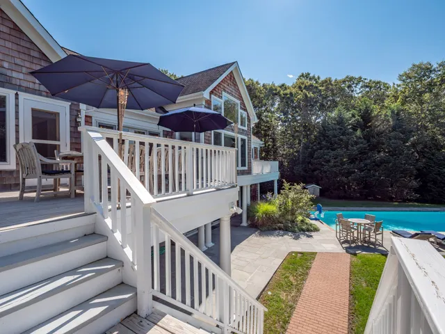 a view of a house with wooden floor and a table and chairs under an umbrella