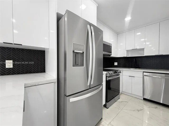 a kitchen with stainless steel appliances granite countertop a refrigerator a stove a sink and white cabinets