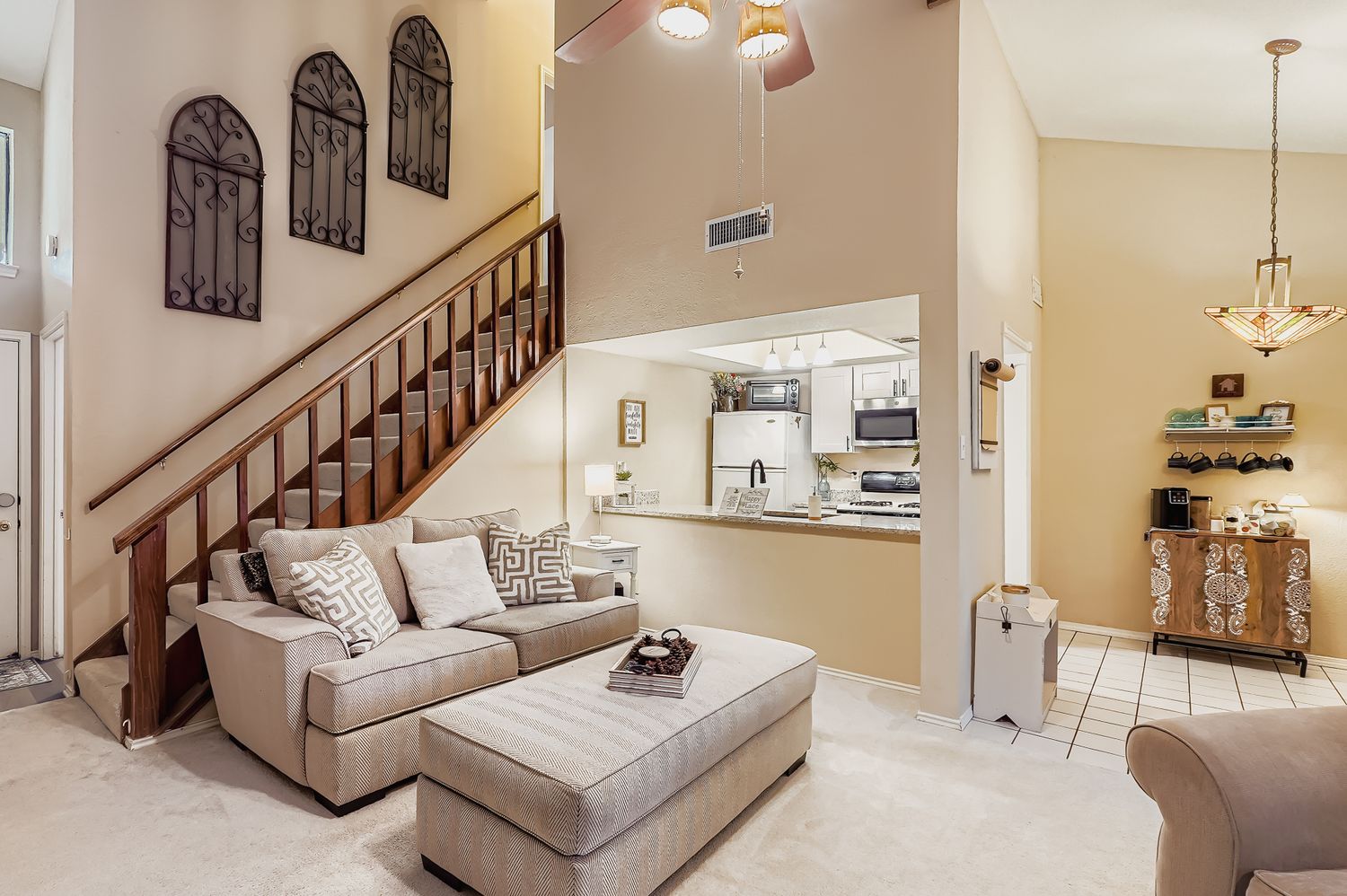 Living room featuring a high ceiling, a ceiling fan, light colored carpet, light tile patterned flooring, and stairway