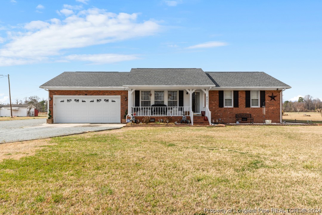 8571 Rhodes Pond Road Dunn, NC 28334 - Photo 2 of 18 a front view of a house with a yard and garage