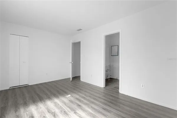 a view of an empty room with wooden floor and closet