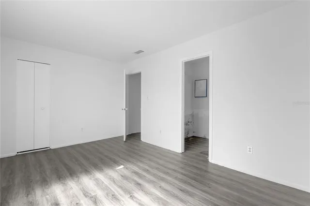 a view of an empty room with wooden floor and closet