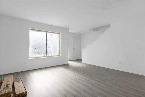 an empty room with wooden floor and windows
