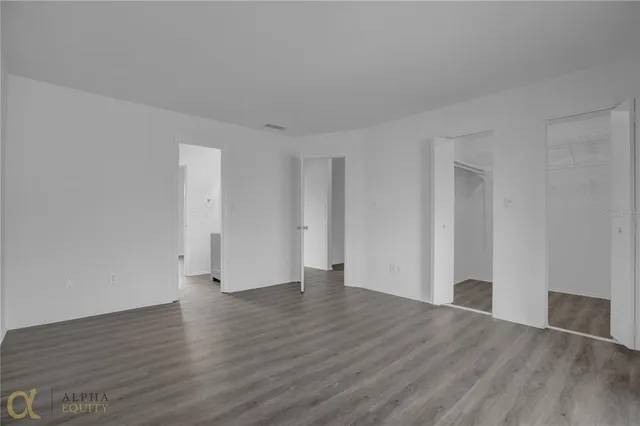 a view of an empty room with wooden floor and closet