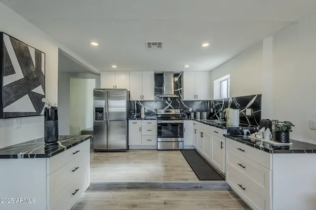 a kitchen with stainless steel appliances kitchen island granite countertop a refrigerator and a stove top oven