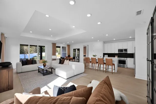 a living room with furniture kitchen view and a large window