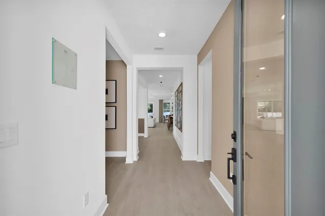 a view of a hallway with wooden floor and a bathroom