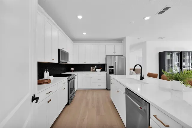 a large white kitchen with stainless steel appliances