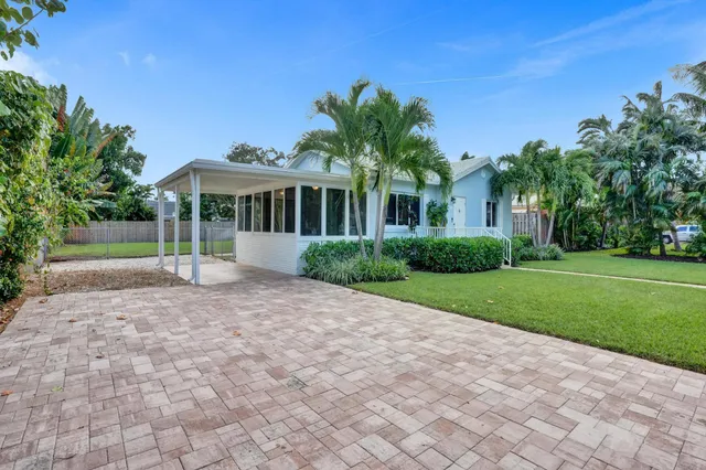a front view of a house with a yard and potted plants