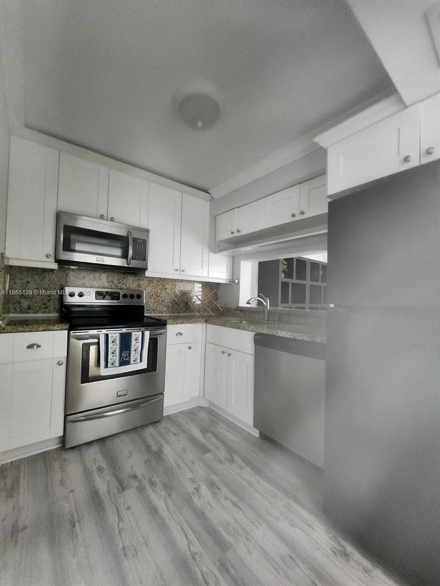 11790 Southwest 18th Street, Unit 2183 Miami, FL 33175 - Photo 12 of 28 a kitchen with granite countertop white cabinets and stainless steel appliances