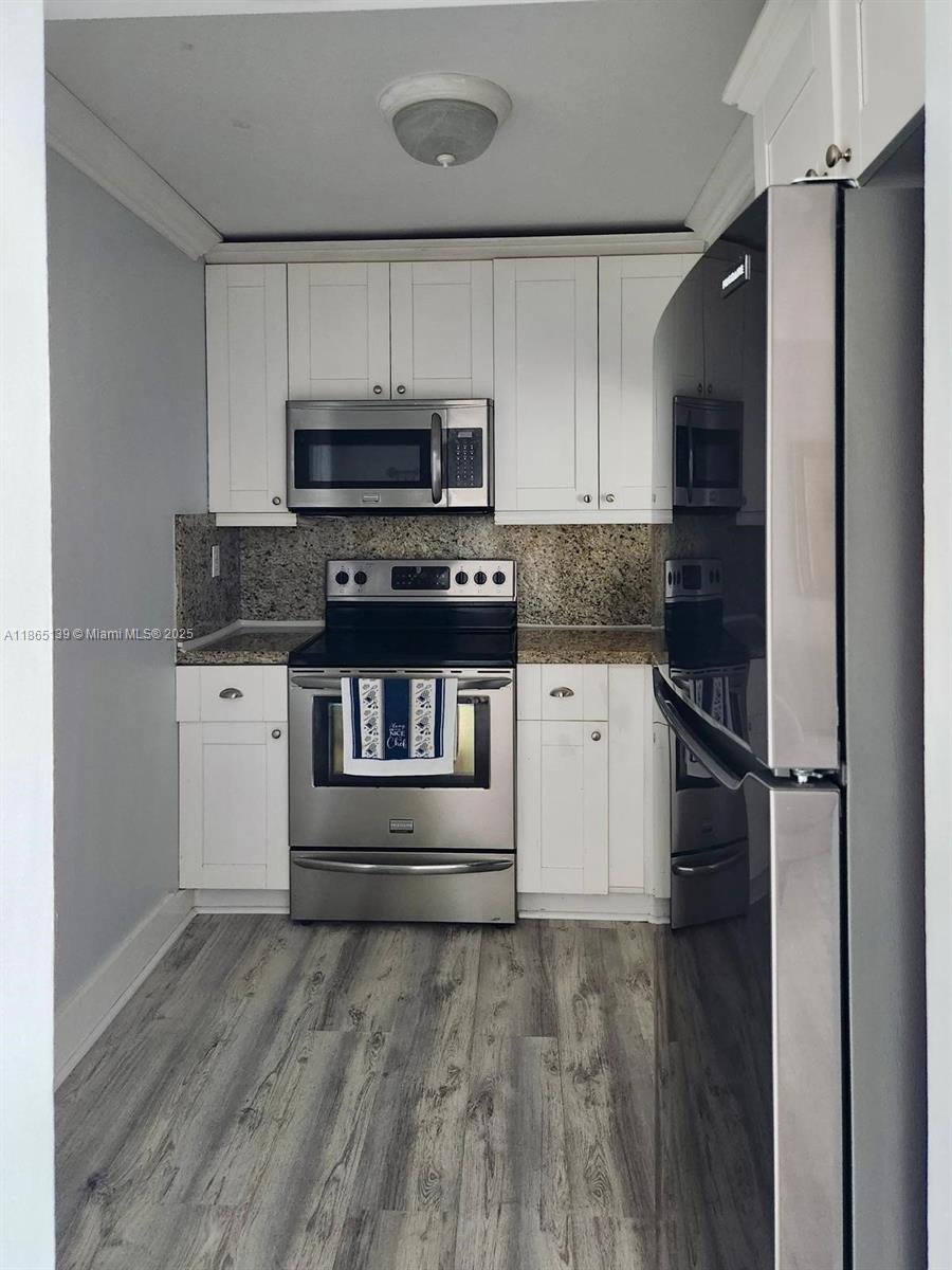 11790 Southwest 18th Street, Unit 2183 Miami, FL 33175 - Photo 14 of 28 a kitchen with granite countertop a refrigerator and a stove top oven