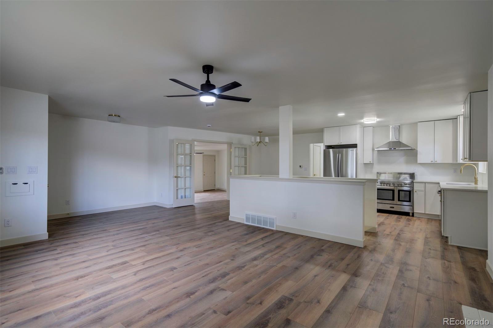 1815 South Monroe Street Denver, CO 80210 - Photo 9 of 37 a view of an empty room with wooden floor and a kitchen