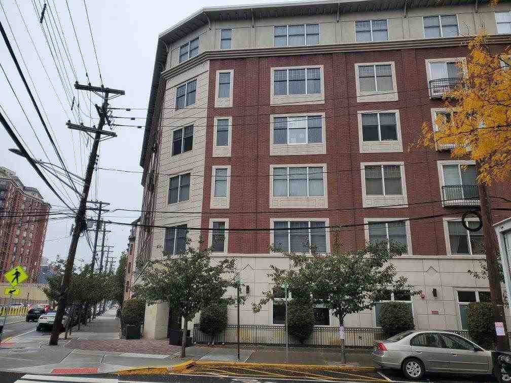 a front view of a building with lot of cars and trees