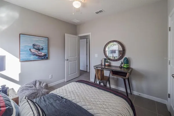 a bedroom with a bed a clock on table and a wall painting