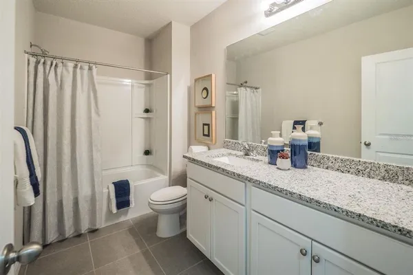 a bathroom with a granite countertop sink a toilet a mirror and shower