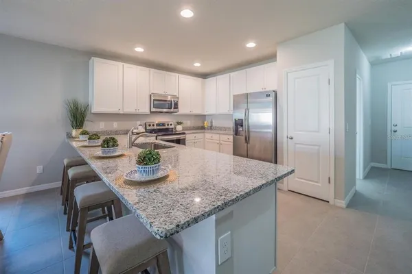 a kitchen with kitchen island granite countertop stainless steel appliances cabinets a dining table and chairs