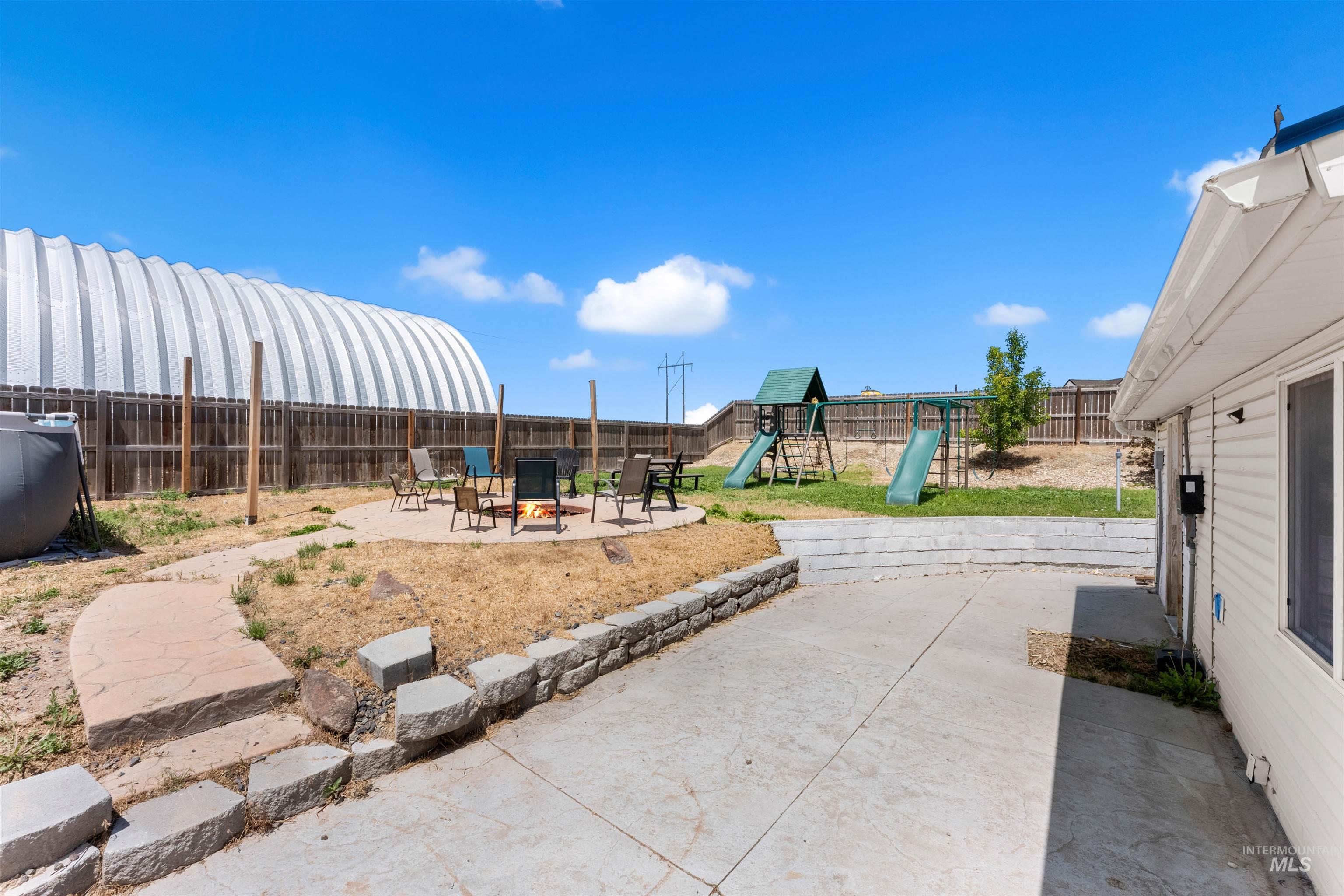 17441 Upper Pleasant Ridge Road Caldwell, ID 83607 - Photo 31 of 40 Expansive backyard featuring a concrete patio, stone retaining walls, and a dedicated fire pit area