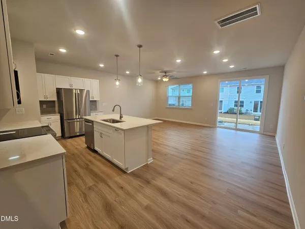 a large kitchen with stainless steel appliances kitchen island a large counter top and a wooden floors