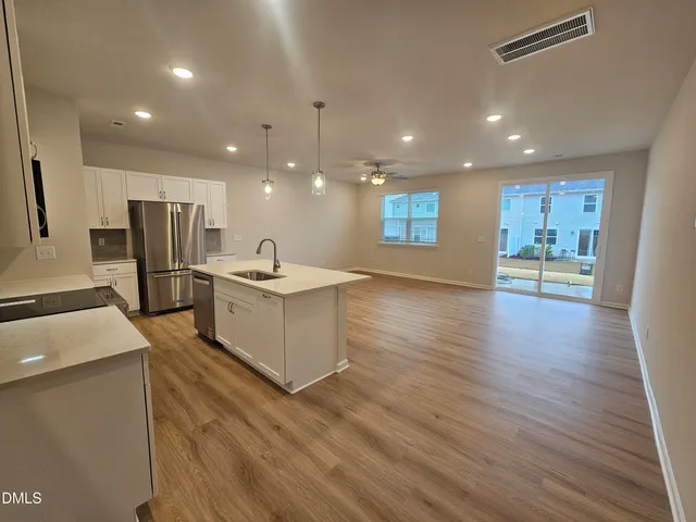 a large kitchen with stainless steel appliances kitchen island a large counter top and a wooden floors