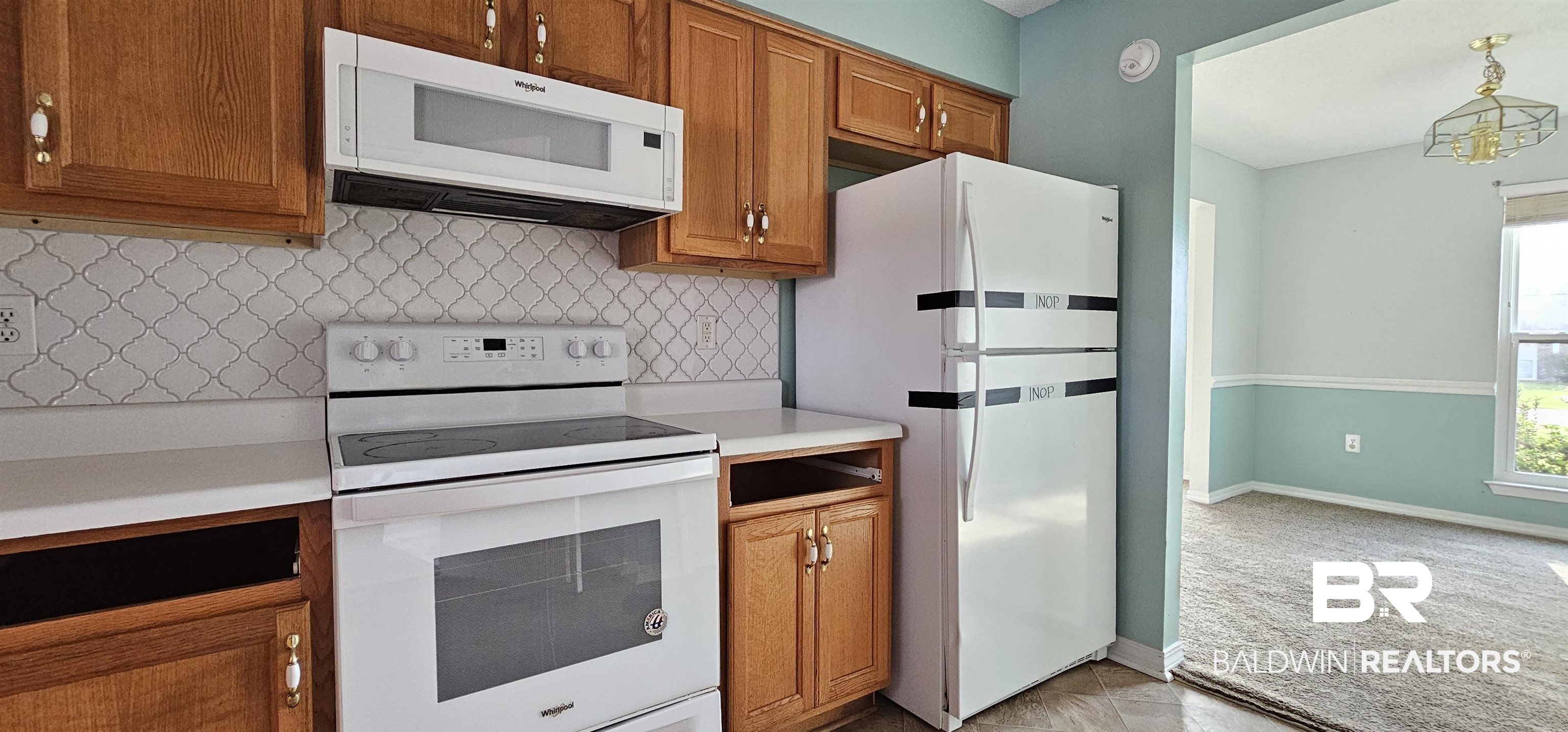8940 Shannon's Mill Road Foley, AL 36535 - Photo 22 of 35 Kitchen with white appliances, backsplash, light countertops, wood finish cabinetry, and light carpet