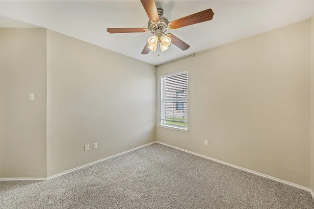 an empty room with a chandelier fan and windows