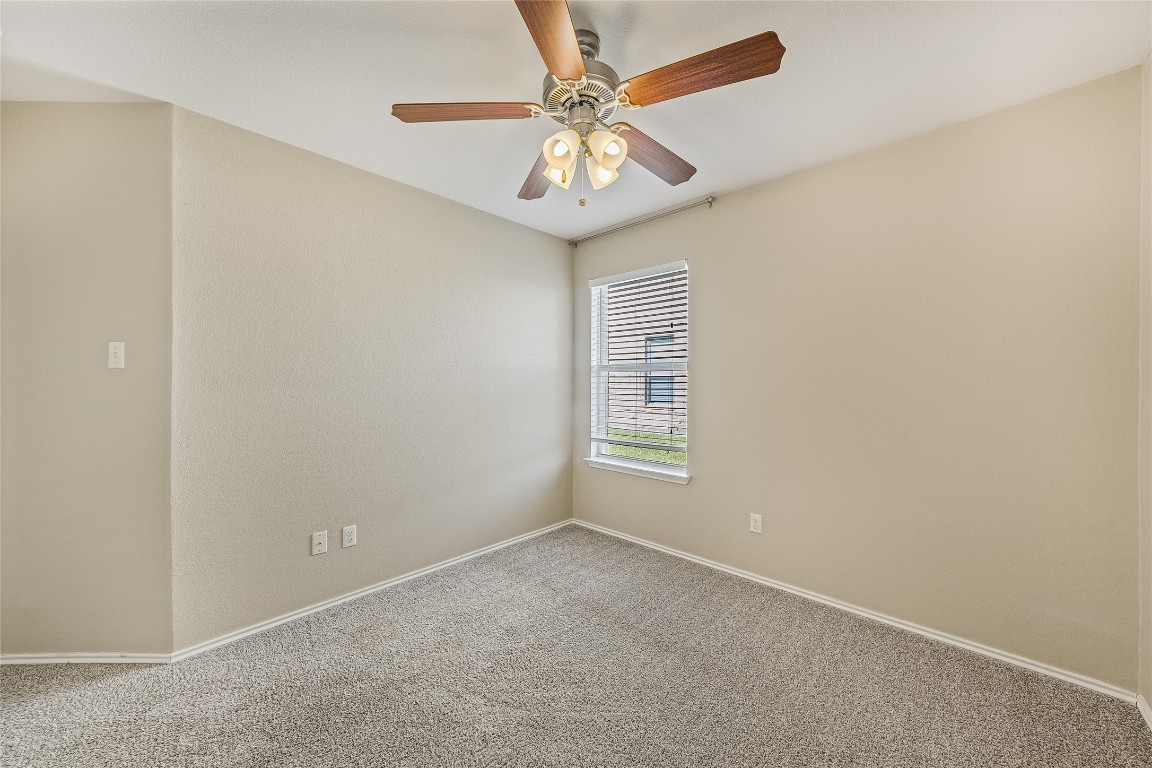 20009 Hawk Hood Drive Pflugerville, TX 78660 - Photo 13 of 16 an empty room with a chandelier fan and windows