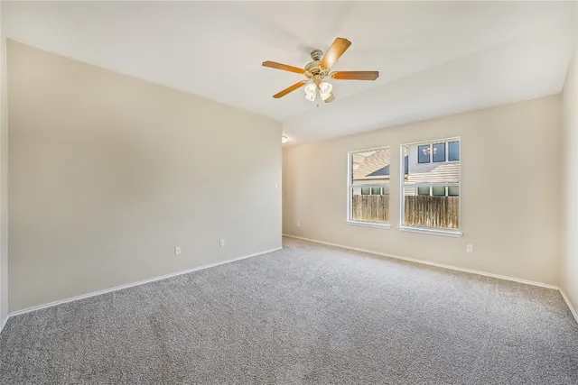 a view of an empty room with chandelier fan and a window