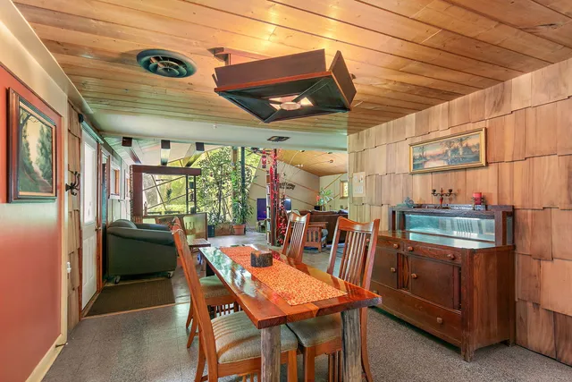 a dining room with stainless steel appliances kitchen island granite countertop a table chairs and a refrigerator