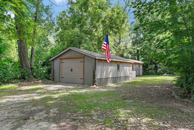 a backyard of a house with plants and large tree