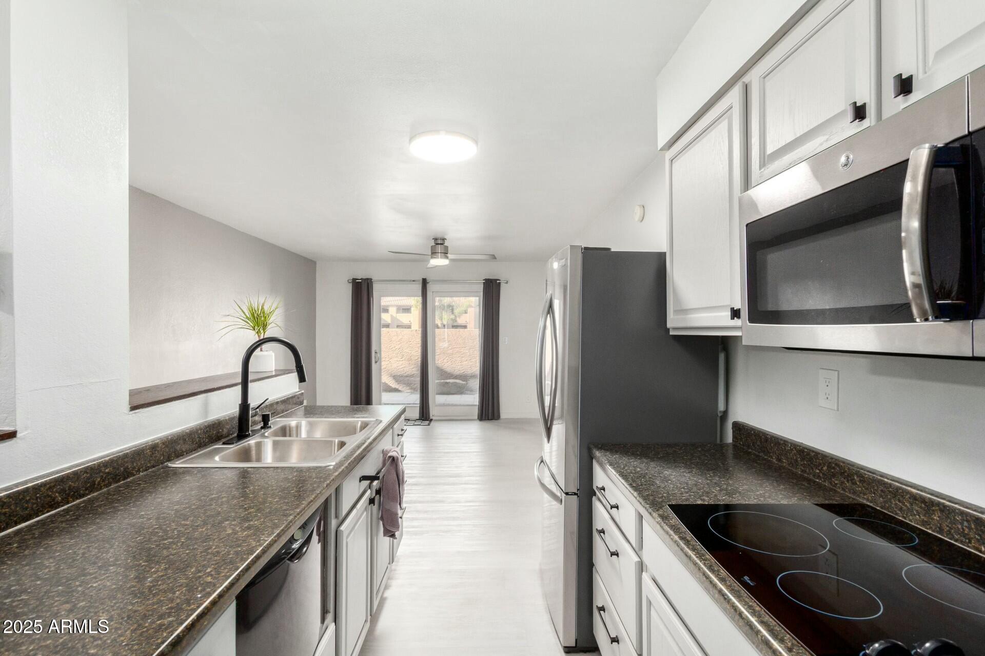 540 North May, Unit 1075 Mesa, AZ 85201 - Photo 13 of 23 a kitchen with stainless steel appliances granite countertop a sink stove and refrigerator