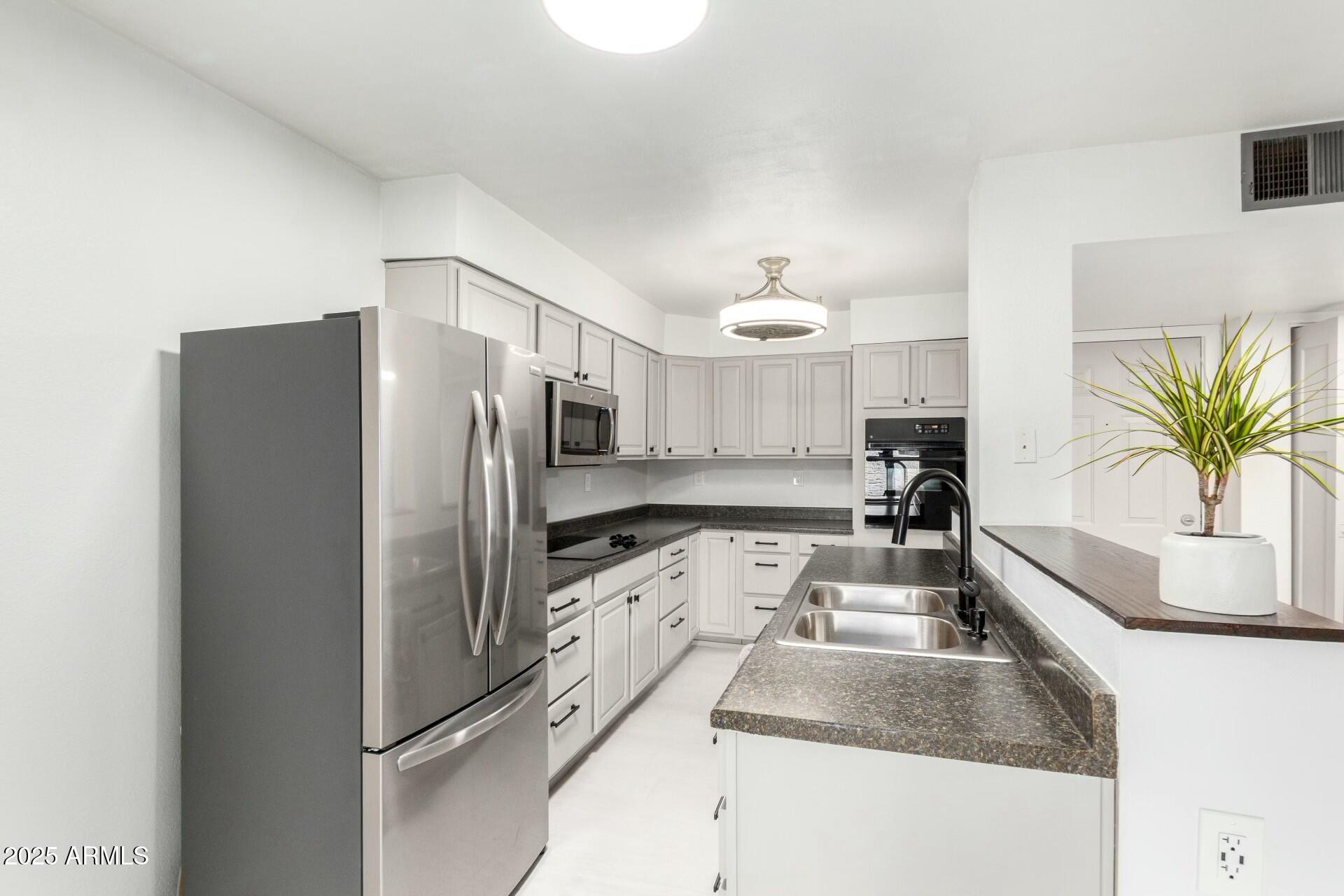 540 North May, Unit 1075 Mesa, AZ 85201 - Photo 14 of 23 a kitchen with granite countertop a refrigerator and a sink