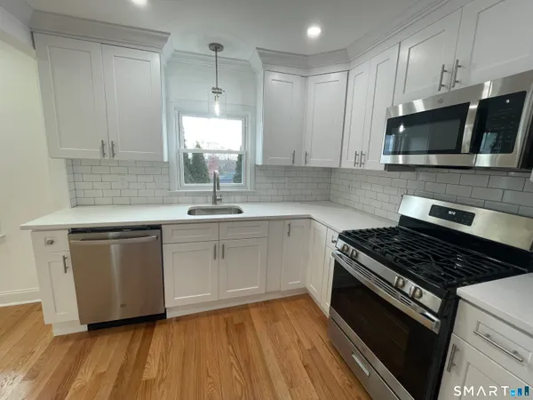 a kitchen with stainless steel appliances a sink dishwasher a stove microwave and cabinets with wooden floor