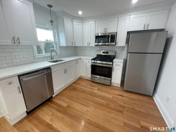 a kitchen with granite countertop a refrigerator a sink dishwasher a stove top oven a refrigerator with island and cabinets