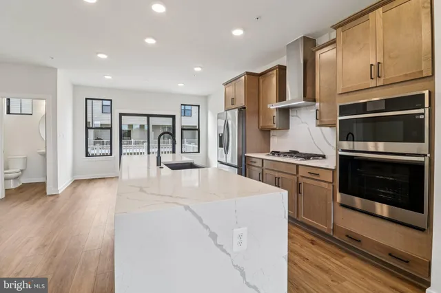 a kitchen with stainless steel appliances kitchen island granite countertop a refrigerator stove oven and wooden floors