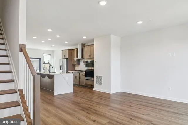 a view of kitchen with refrigerator stove and wooden floor