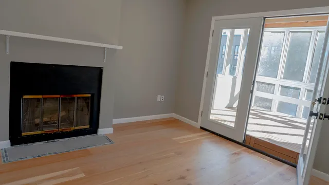 a view of an empty room with a fireplace and window
