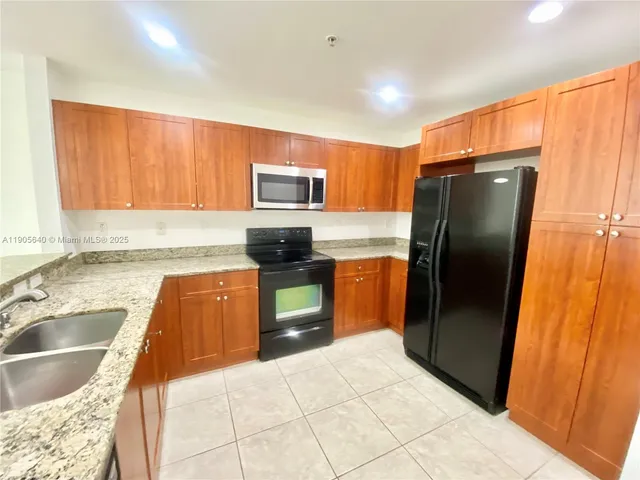 a kitchen with stainless steel appliances granite countertop a refrigerator a stove a sink and dishwasher