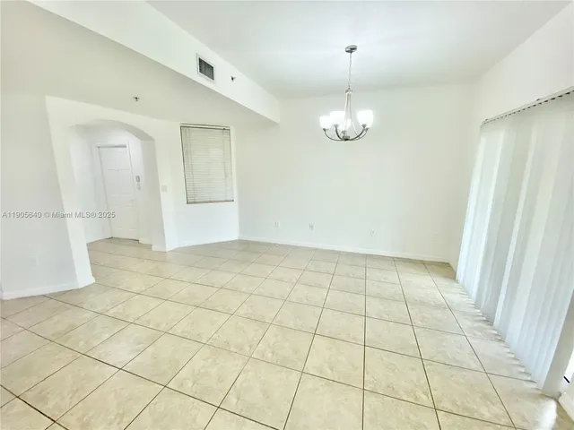 an empty room with kitchen and chandelier fan