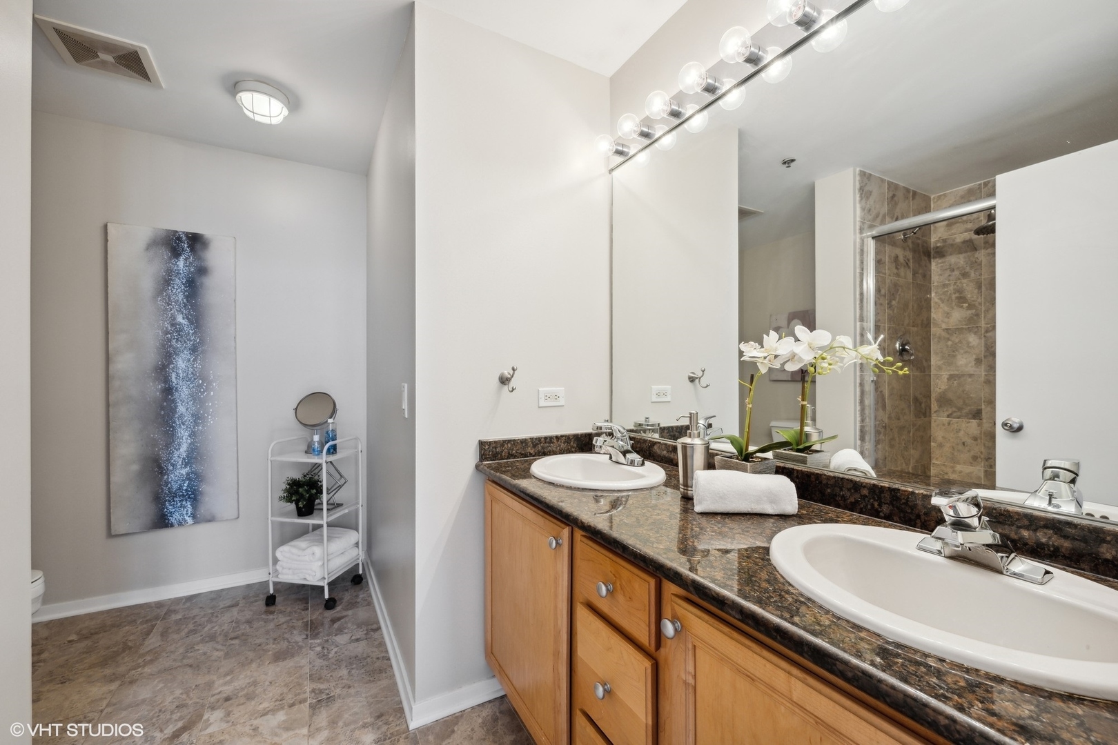 500 South Clinton Street, Unit 410 Chicago, IL 60607 - Photo 12 of 17 a bathroom with double vanity sinks a toilet a mirror and shower