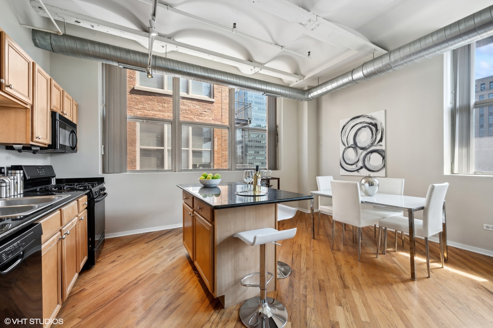 500 South Clinton Street, Unit 410 Chicago, IL 60607 - Photo 7 of 17 a kitchen with stainless steel appliances granite countertop a stove a refrigerator a dining table and chairs with wooden floor
