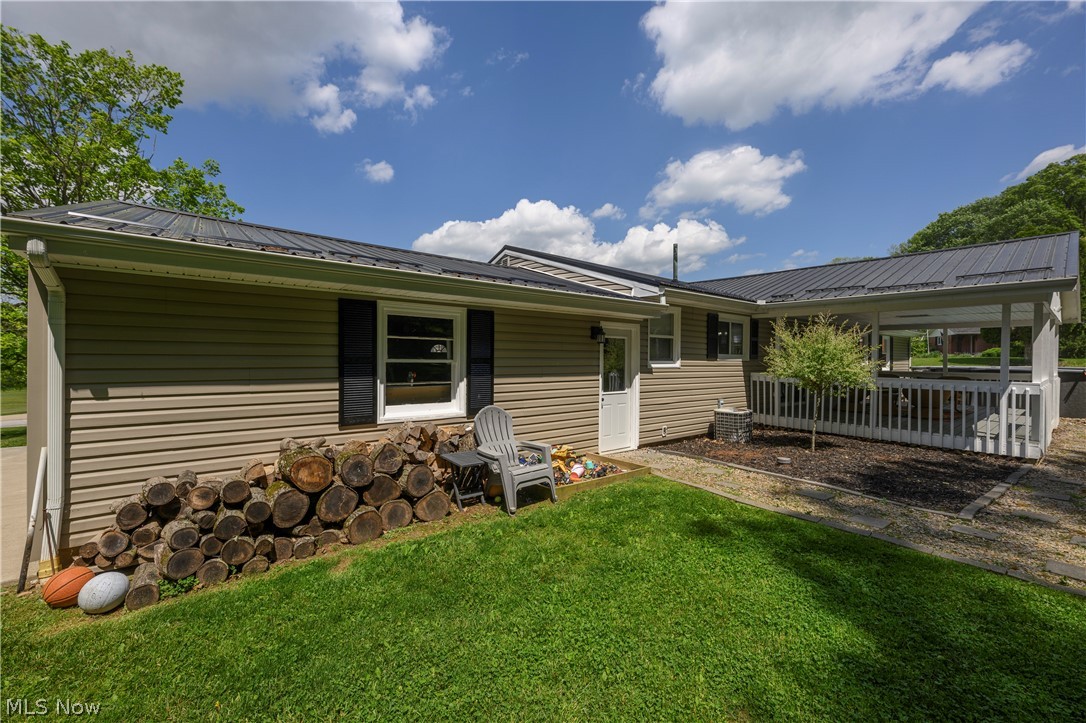 6105 Wolf Run Road Southeast Dennison, OH 44621 - Photo 10 of 35 Exterior featuring tan siding, a dark metal roof, and black window shutters