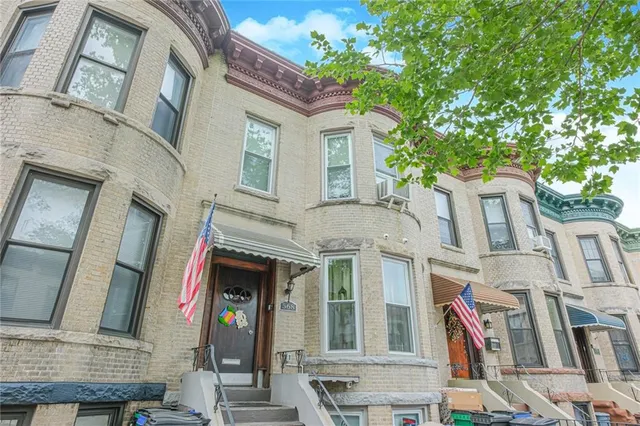a front view of a residential apartment building with a tree