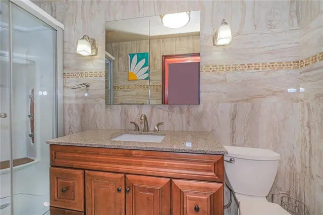 a bathroom with a granite countertop toilet sink and mirror