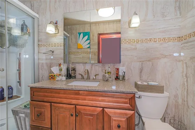 a bathroom with a granite countertop toilet sink and mirror